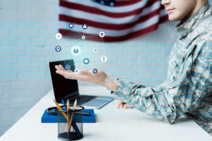 cropped view of soldier gesturing near laptop with blank screen and data visualization